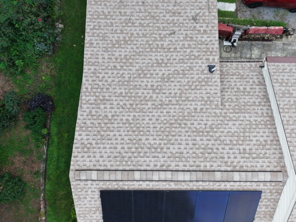 Close-up of asphalt shingle roofing and a roof vent near the solar array